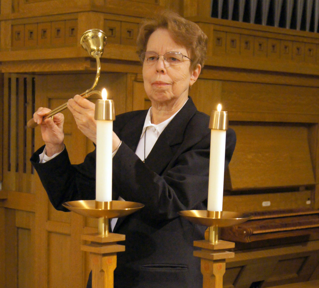 Sister Jeanne Ann Weber lights the altar candles.