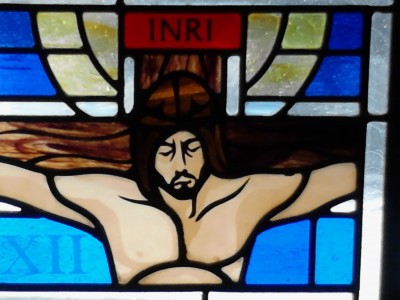 image of Jesus hanging on the cross from a colorful stained glass window