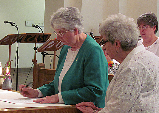 Sister Beverly Raway, signs her renewal of perpetual monastic profession.